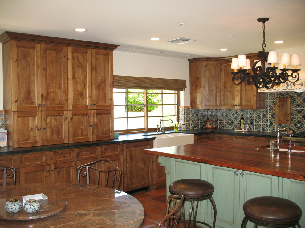 Bild på ett stort amerikanskt kök, med en rustik diskho, luckor med infälld panel, skåp i slitet trä, träbänkskiva, flerfärgad stänkskydd, stänkskydd i terrakottakakel, integrerade vitvaror, målat trägolv och en köksö