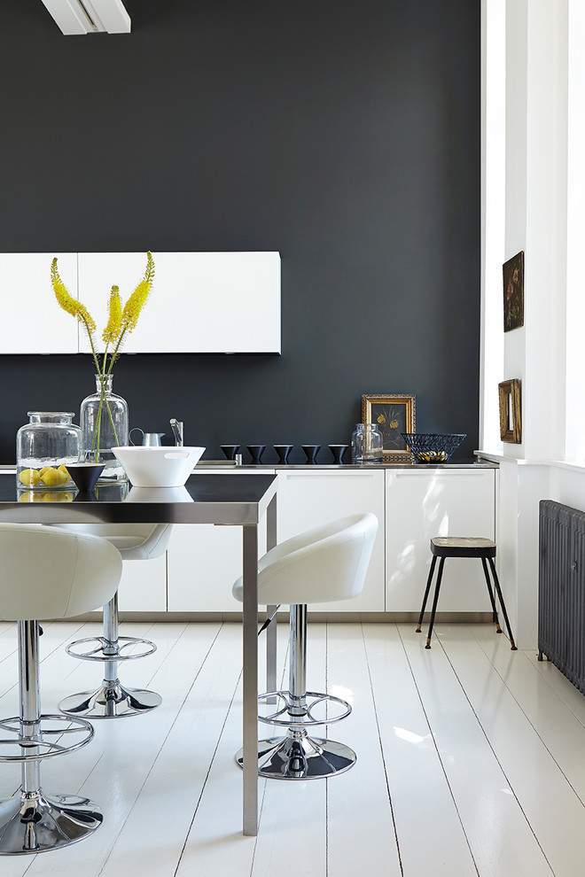 Contemporary kitchen in Belfast with flat-panel cabinets, black splashback, an island and white floors.