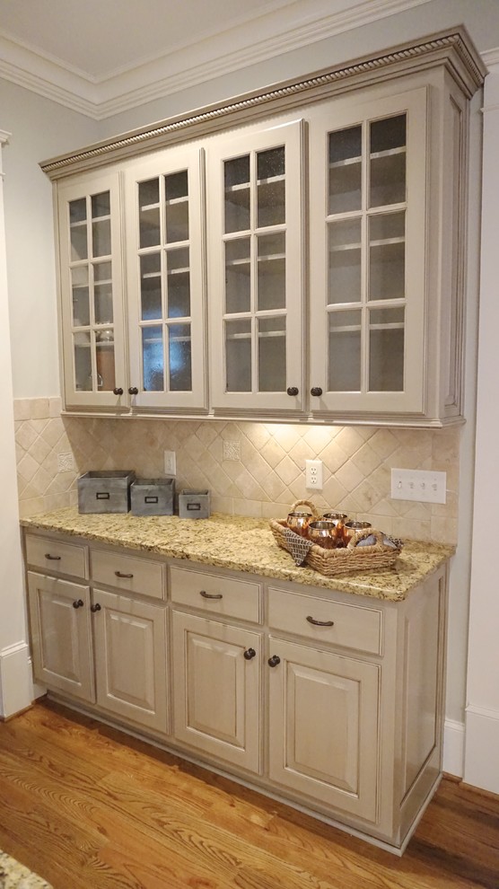Inredning av ett klassiskt stort kök, med en undermonterad diskho, luckor med upphöjd panel, grå skåp, granitbänkskiva, beige stänkskydd, stänkskydd i stenkakel, rostfria vitvaror, mellanmörkt trägolv och en köksö