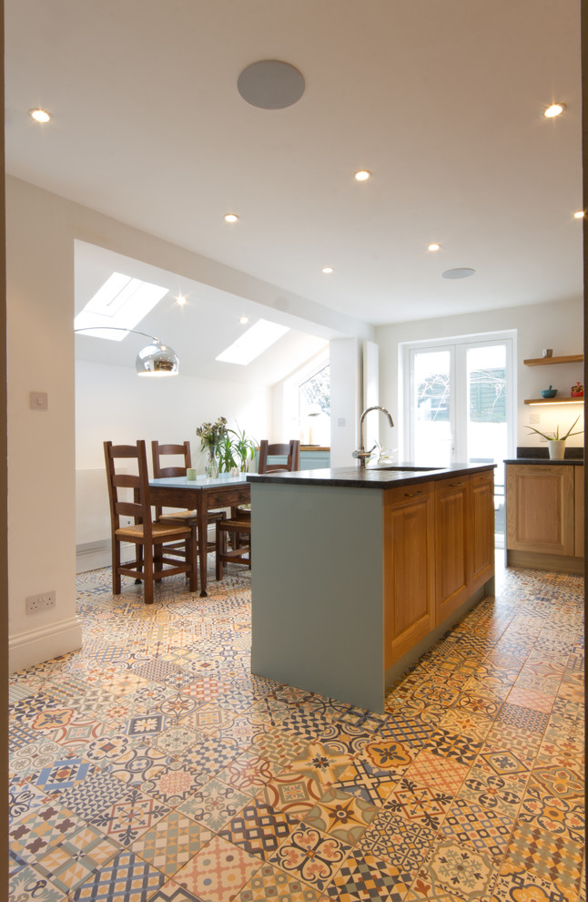 Design ideas for a large traditional l-shaped kitchen/diner in London with a single-bowl sink, raised-panel cabinets, medium wood cabinets, quartz worktops, multi-coloured splashback, ceramic splashback, coloured appliances, porcelain flooring and an island.
