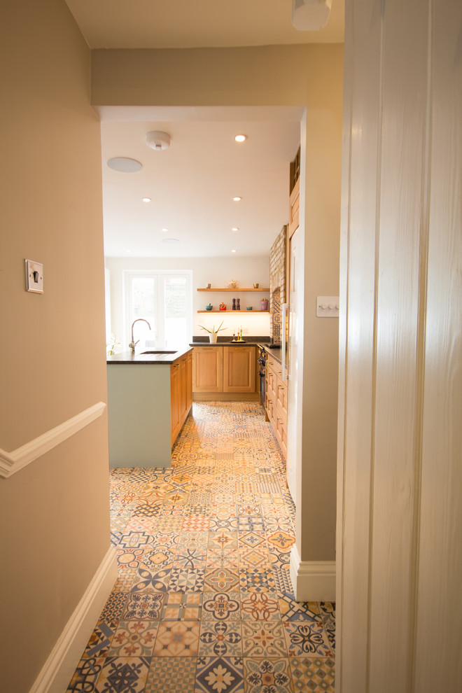 Photo of a large traditional l-shaped kitchen/diner in London with a single-bowl sink, raised-panel cabinets, medium wood cabinets, quartz worktops, multi-coloured splashback, ceramic splashback, coloured appliances, porcelain flooring and an island.