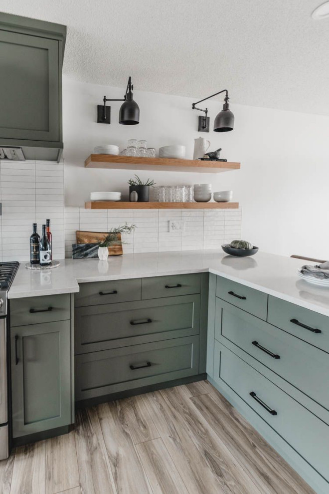 Bild på ett mellanstort funkis vit vitt kök, med en rustik diskho, gröna skåp, bänkskiva i kvarts, vitt stänkskydd, stänkskydd i keramik, rostfria vitvaror, ljust trägolv, en halv köksö, brunt golv och skåp i shakerstil