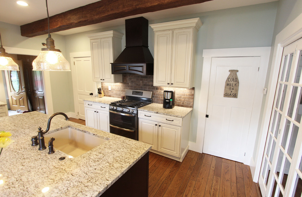 Exempel på ett mellanstort klassiskt kök, med en enkel diskho, släta luckor, beige skåp, granitbänkskiva, brunt stänkskydd, stänkskydd i tegel, rostfria vitvaror, mellanmörkt trägolv och en köksö