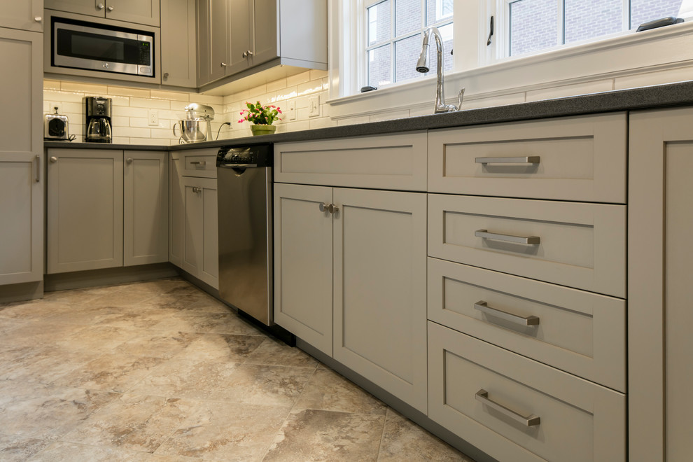 Photo of a medium sized classic l-shaped kitchen/diner in Burlington with a built-in sink, shaker cabinets, grey cabinets, laminate countertops, white splashback, ceramic splashback, stainless steel appliances, ceramic flooring and an island.