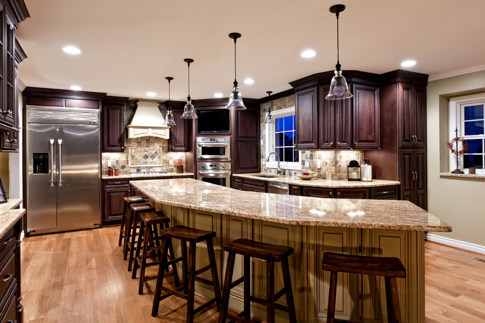Exempel på ett stort klassiskt kök, med en undermonterad diskho, luckor med upphöjd panel, skåp i mörkt trä, granitbänkskiva, flerfärgad stänkskydd, stänkskydd i stenkakel, rostfria vitvaror, mellanmörkt trägolv, en köksö och brunt golv