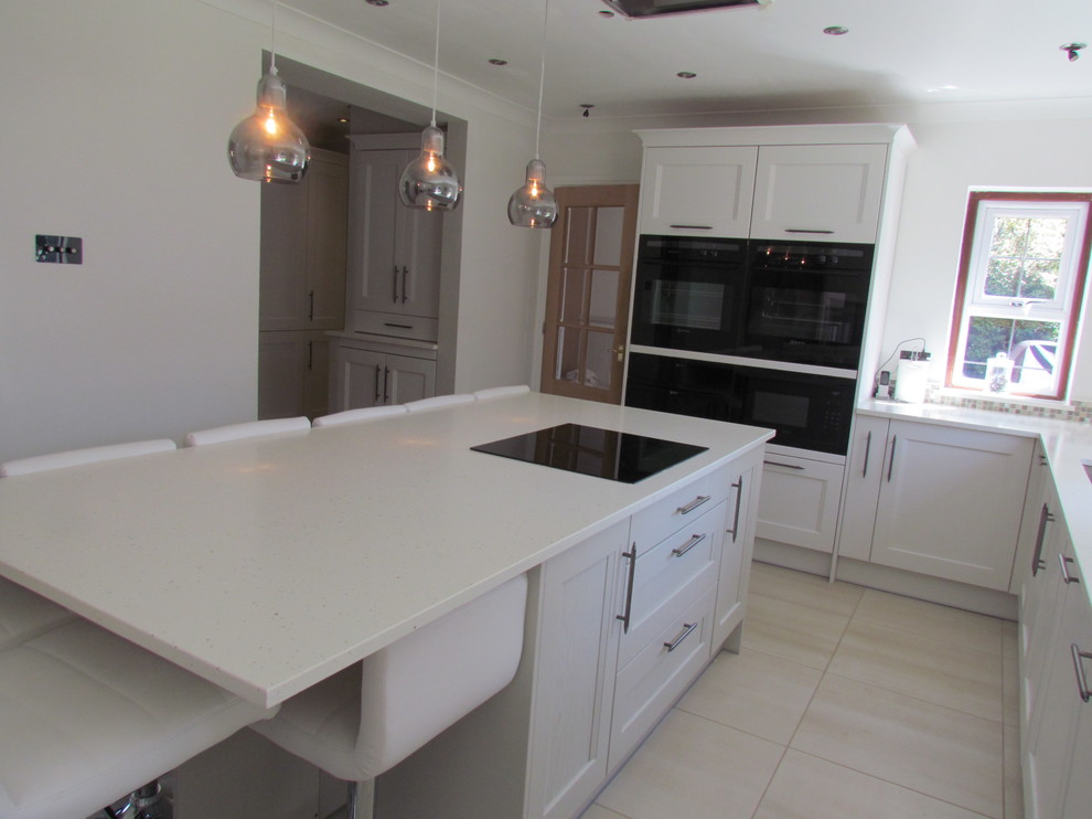 Foto de cocina clásica de tamaño medio con armarios estilo shaker, puertas de armario blancas, encimera de granito, electrodomésticos negros y una isla