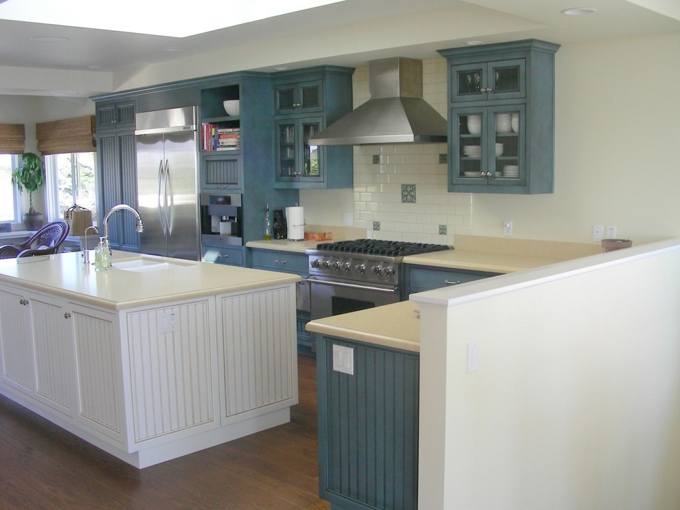Imagen de cocina moderna de tamaño medio con puertas de armario azules, electrodomésticos de acero inoxidable y una isla