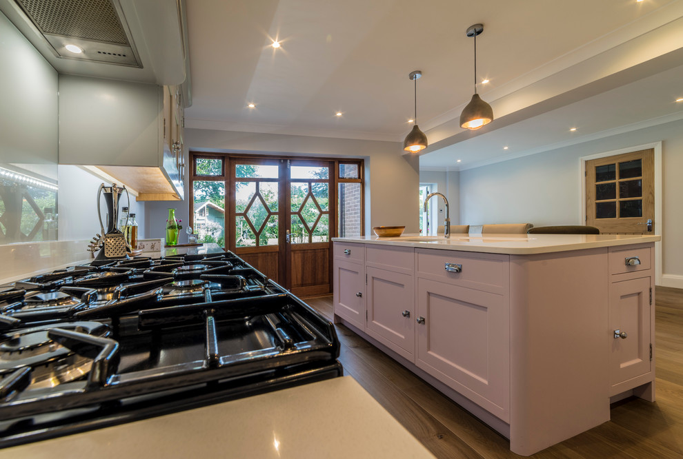 Moderne Küche mit Schrankfronten im Shaker-Stil, Quarzit-Arbeitsplatte, Küchenrückwand in Weiß, hellem Holzboden und Kücheninsel in Cheshire