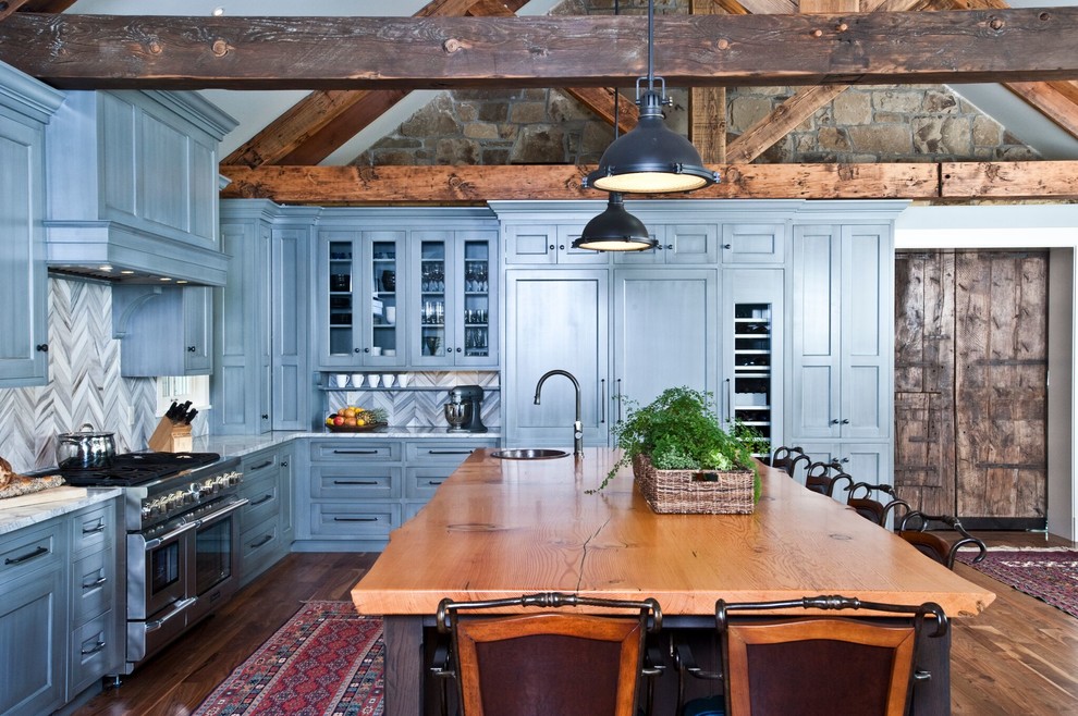 Inredning av ett rustikt stort kök, med stänkskydd i stenkakel, rostfria vitvaror, mellanmörkt trägolv, en köksö, en rustik diskho, luckor med infälld panel, grå skåp, granitbänkskiva, grått stänkskydd och brunt golv