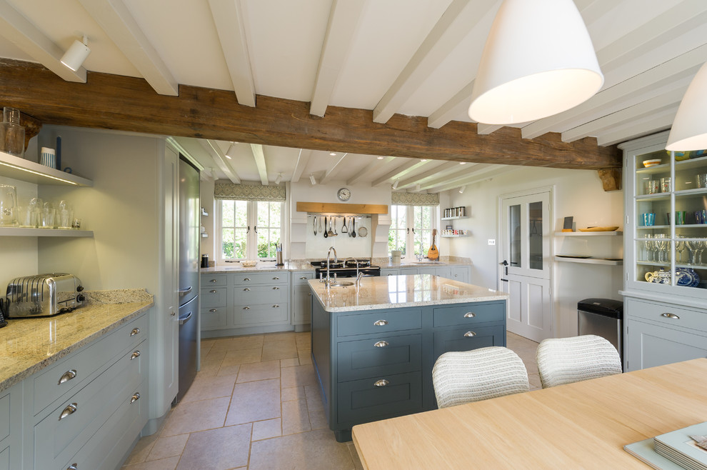 Traditional kitchen in Hampshire with a submerged sink, recessed-panel cabinets, blue cabinets, grey splashback, glass sheet splashback, stainless steel appliances and porcelain flooring.