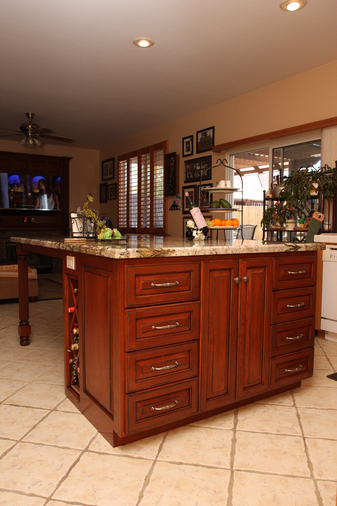 Klassisk inredning av ett mellanstort kök, med en dubbel diskho, luckor med upphöjd panel, skåp i mellenmörkt trä, granitbänkskiva, flerfärgad stänkskydd, glaspanel som stänkskydd, rostfria vitvaror, klinkergolv i porslin och en köksö