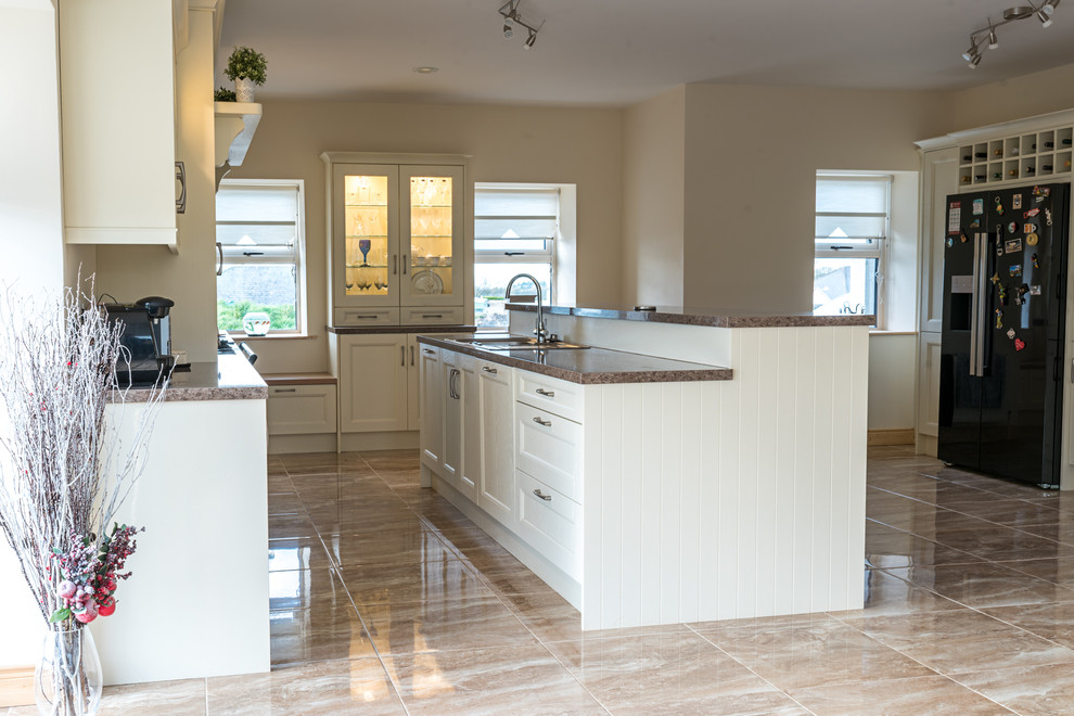 Example of a large transitional eat-in kitchen design in Other with flat-panel cabinets, laminate countertops and an island