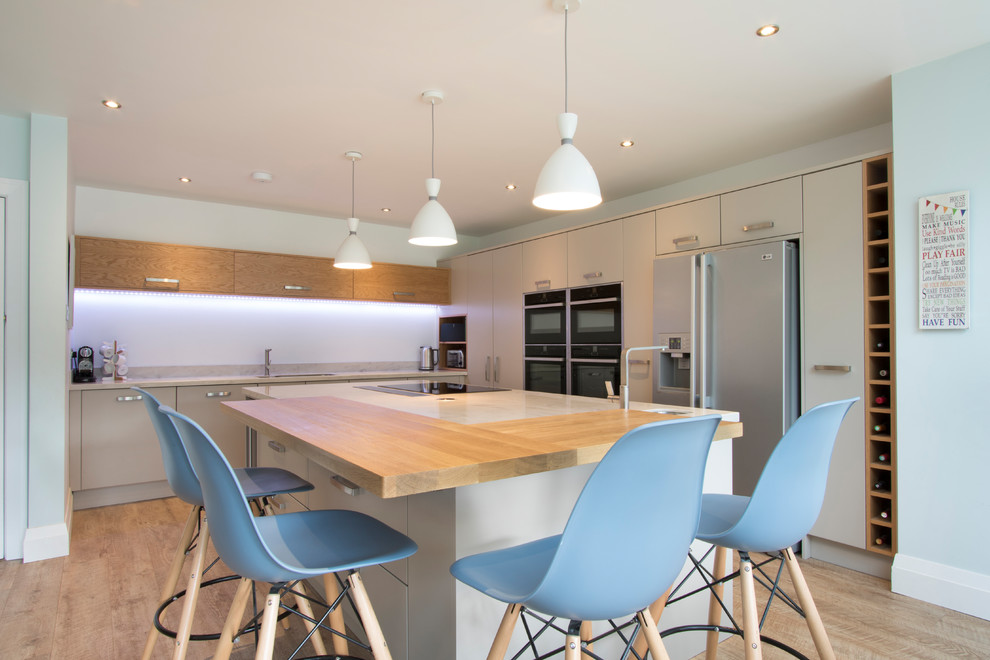 Mittelgroße Moderne Küche in L-Form mit flächenbündigen Schrankfronten, beigen Schränken, hellem Holzboden, Kücheninsel und braunem Boden in Sonstige