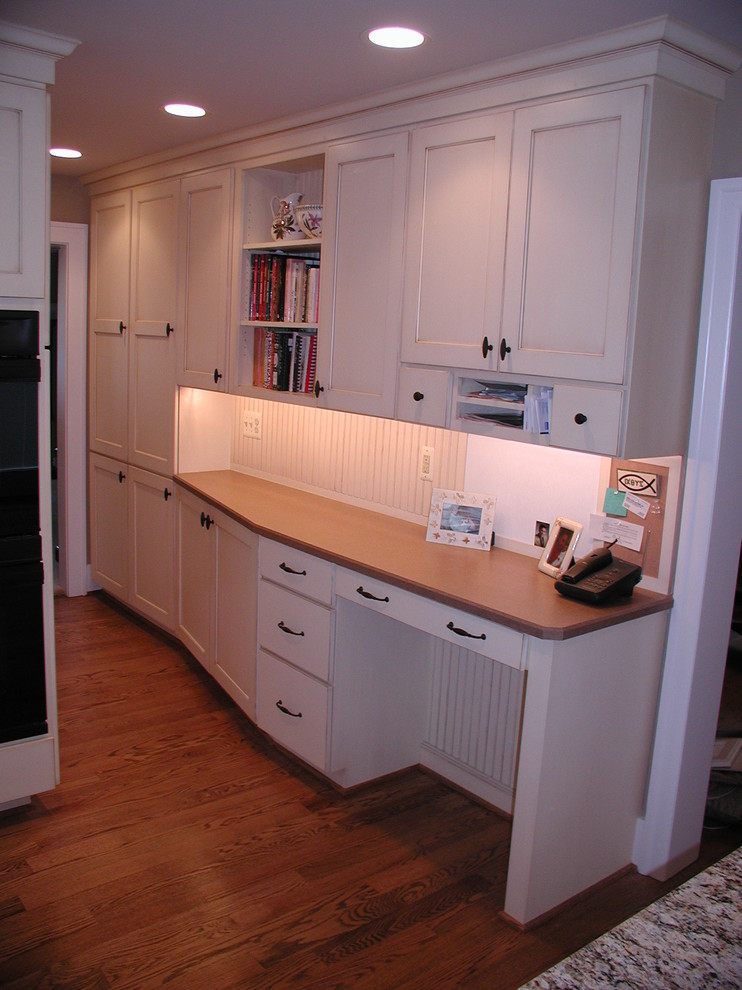 Modelo de cocina tradicional con fregadero bajoencimera, armarios con paneles lisos, puertas de armario blancas, encimera de granito, salpicadero blanco y electrodomésticos con paneles