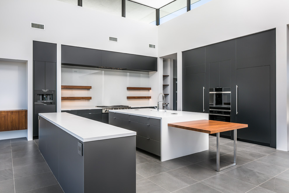 Inspiration for an expansive contemporary l-shaped open plan kitchen in Phoenix with a submerged sink, flat-panel cabinets, grey cabinets, engineered stone countertops, white splashback, glass sheet splashback, integrated appliances, porcelain flooring, multiple islands, grey floors and white worktops.
