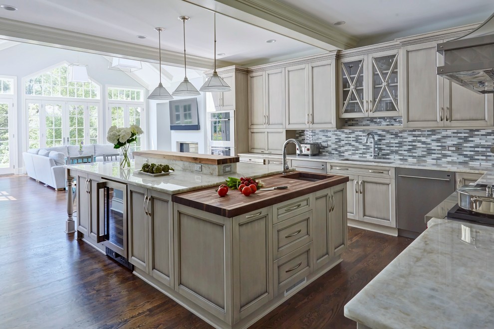 Inspiration for a huge timeless l-shaped medium tone wood floor open concept kitchen remodel in Chicago with a single-bowl sink, recessed-panel cabinets, gray cabinets, quartzite countertops, multicolored backsplash, mosaic tile backsplash, stainless steel appliances and an island