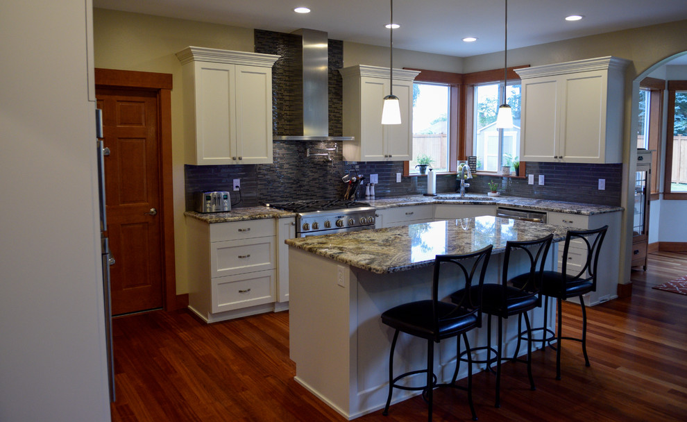 Exempel på ett mellanstort klassiskt kök, med en undermonterad diskho, skåp i shakerstil, vita skåp, granitbänkskiva, grått stänkskydd, rostfria vitvaror, mellanmörkt trägolv, en köksö, stänkskydd i glaskakel och brunt golv
