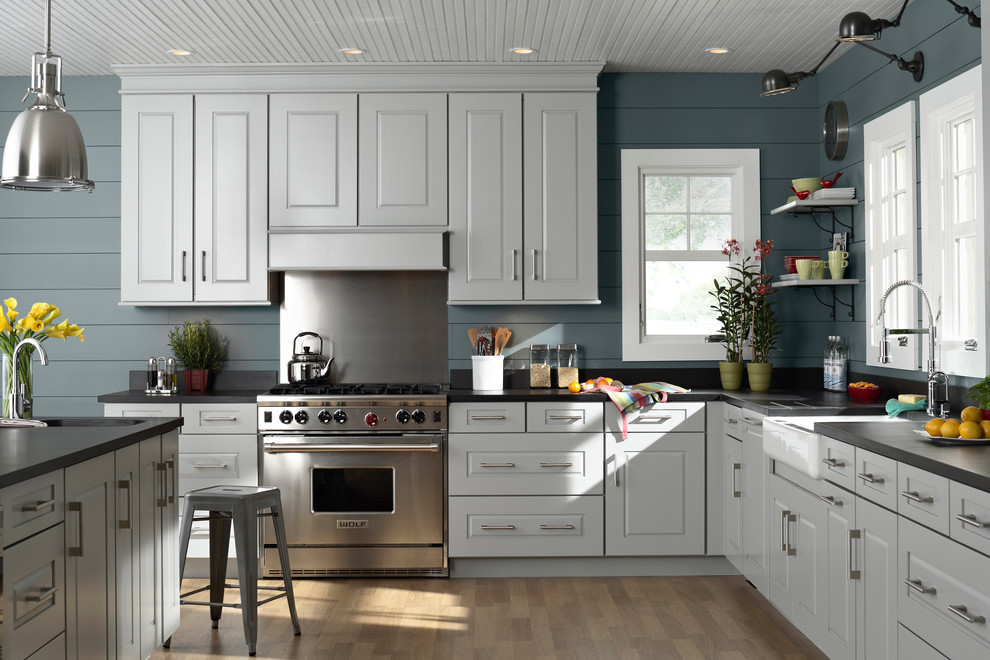 Example of a mid-sized classic l-shaped light wood floor eat-in kitchen design in Denver with a double-bowl sink, raised-panel cabinets, white cabinets, quartz countertops, stainless steel appliances and an island