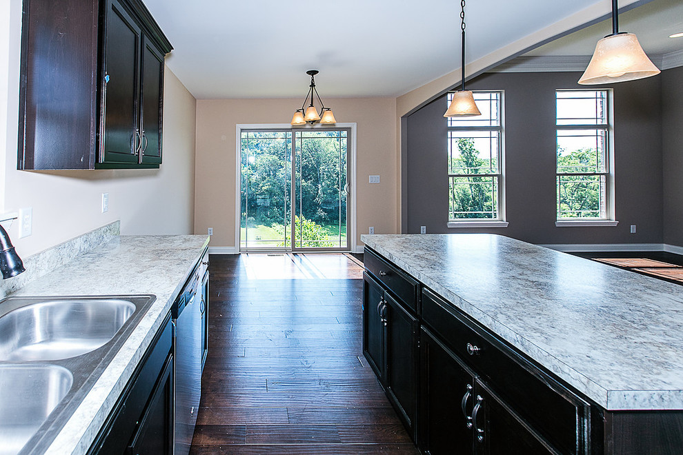Open concept kitchen - mid-sized traditional single-wall dark wood floor and brown floor open concept kitchen idea in Louisville with a double-bowl sink, shaker cabinets, black cabinets, stainless steel appliances, an island and laminate countertops