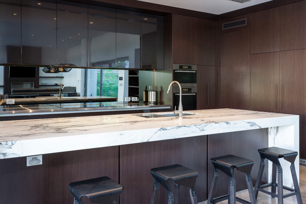 Inspiration for a large contemporary l-shaped kitchen/diner in Perth with a submerged sink, flat-panel cabinets, light wood cabinets, marble worktops, metallic splashback, glass sheet splashback, stainless steel appliances, limestone flooring and an island.