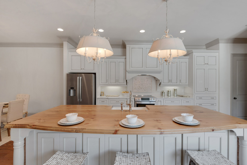 Large beach style single-wall light wood floor open concept kitchen photo in Miami with a farmhouse sink, recessed-panel cabinets, white cabinets, marble countertops, white backsplash, subway tile backsplash, stainless steel appliances and an island