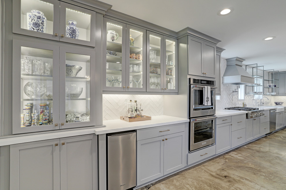Klassisk inredning av ett mellanstort vit vitt kök, med en rustik diskho, luckor med infälld panel, grå skåp, granitbänkskiva, vitt stänkskydd, stänkskydd i tunnelbanekakel, rostfria vitvaror, cementgolv, en köksö och grått golv