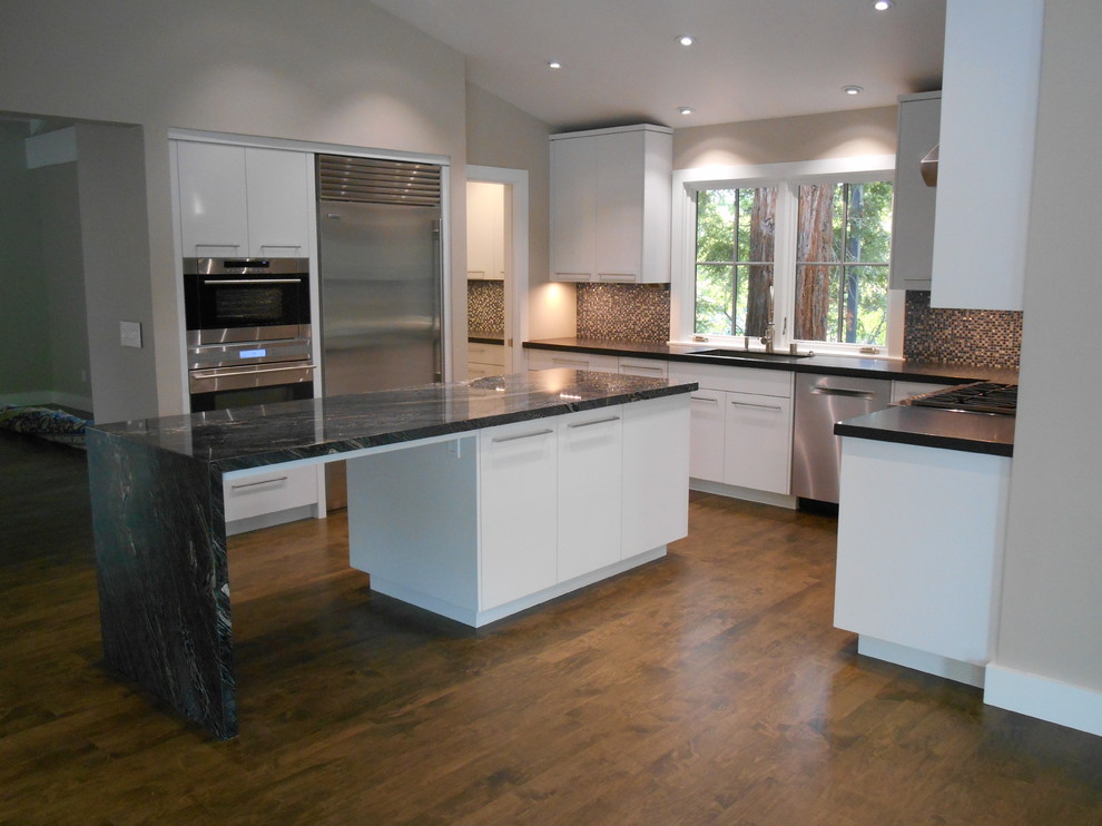 Bild på ett mellanstort funkis u-kök, med en undermonterad diskho, släta luckor, granitbänkskiva, grått stänkskydd, stänkskydd i mosaik, rostfria vitvaror, mellanmörkt trägolv och en köksö