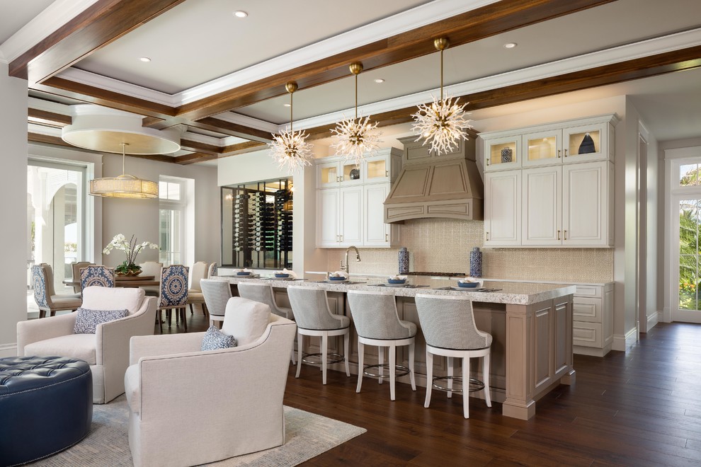 Large beach style l-shaped dark wood floor and brown floor open concept kitchen photo in Miami with raised-panel cabinets, white cabinets, beige backsplash, an island, beige countertops, an undermount sink and paneled appliances