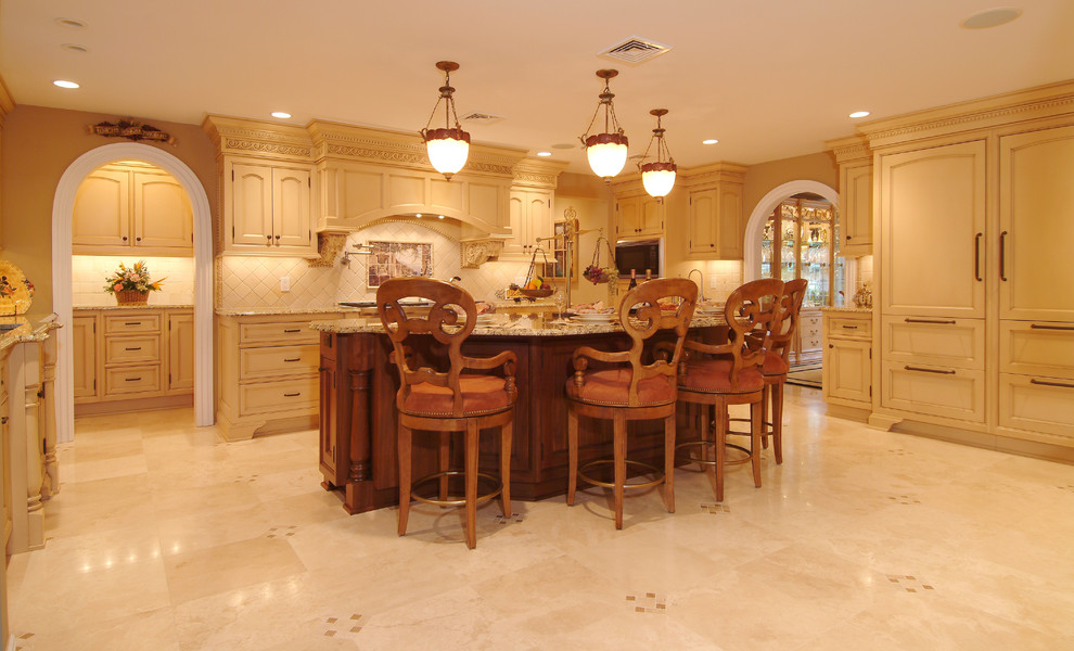 Large tuscan marble floor kitchen photo in New York with recessed-panel cabinets, paneled appliances, an island, an undermount sink, granite countertops, beige backsplash and yellow cabinets