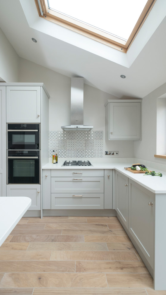 Mid-sized elegant u-shaped ceramic tile kitchen photo in Cardiff with an undermount sink, shaker cabinets, gray cabinets, quartzite countertops, gray backsplash, ceramic backsplash, stainless steel appliances and a peninsula