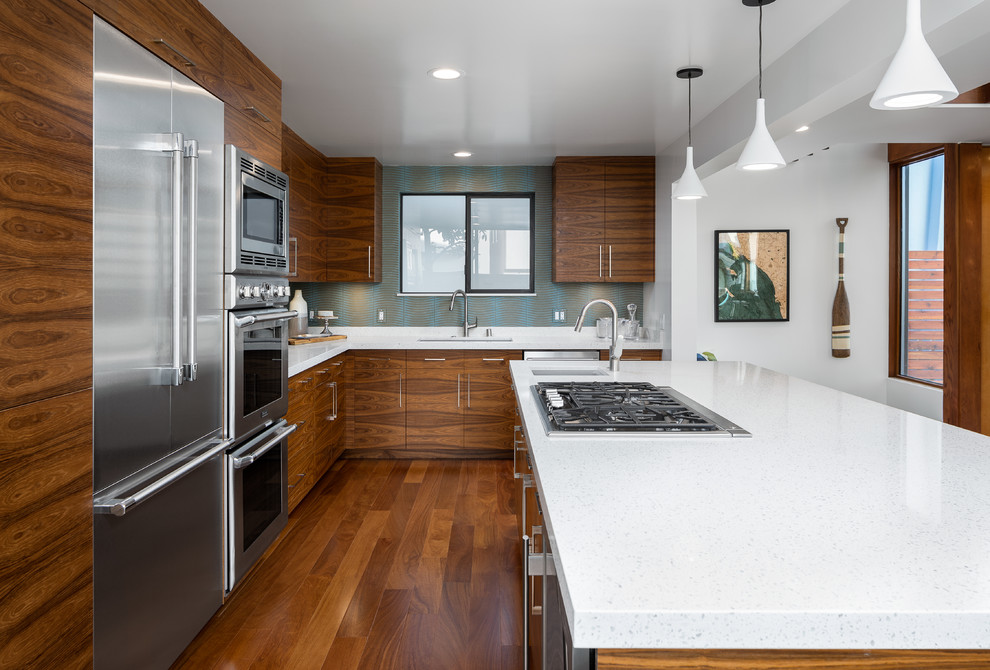 Example of a large 1950s medium tone wood floor and brown floor eat-in kitchen design in Los Angeles with a drop-in sink, flat-panel cabinets, medium tone wood cabinets, quartzite countertops, multicolored backsplash, stainless steel appliances, an island and white countertops