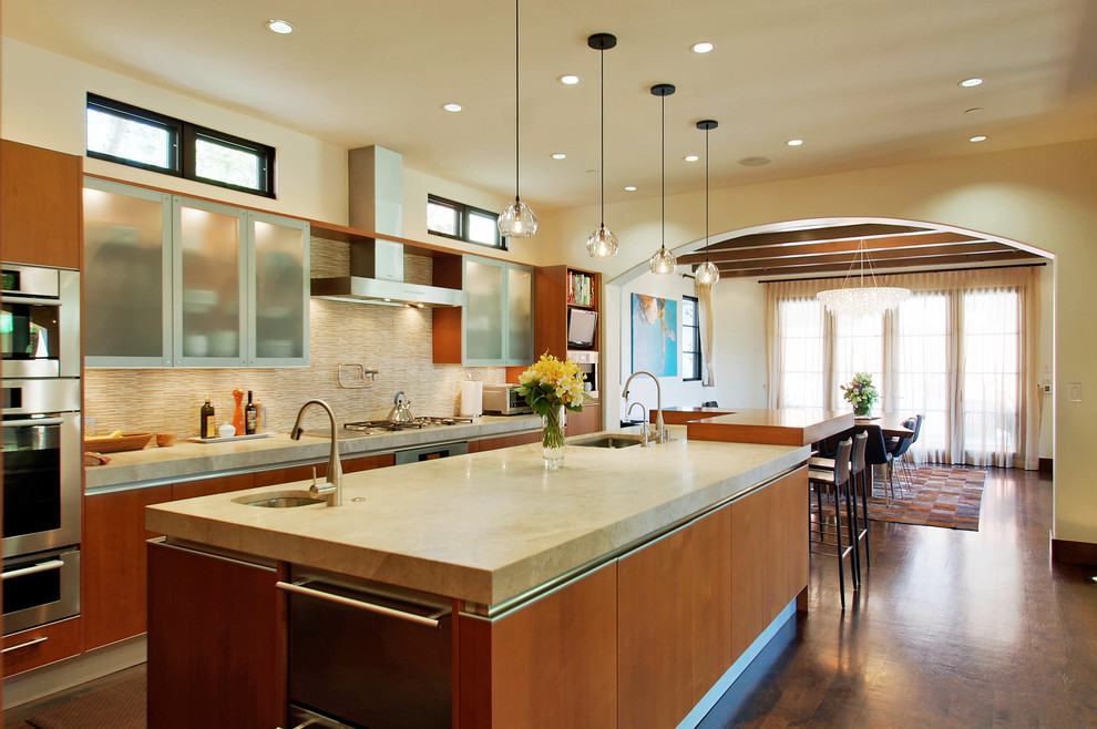 Photo of a mediterranean l-shaped kitchen/diner in Los Angeles with beige splashback, matchstick tiled splashback, a submerged sink, flat-panel cabinets, medium wood cabinets, stainless steel appliances, medium hardwood flooring and an island.