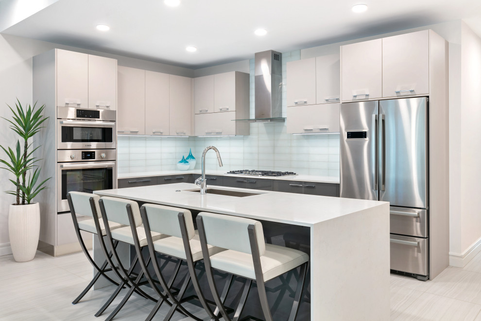 Photo of a contemporary l-shaped kitchen in Tampa with a submerged sink, flat-panel cabinets, engineered stone countertops, white splashback, glass tiled splashback, stainless steel appliances, porcelain flooring, an island, white worktops, beige cabinets and beige floors.