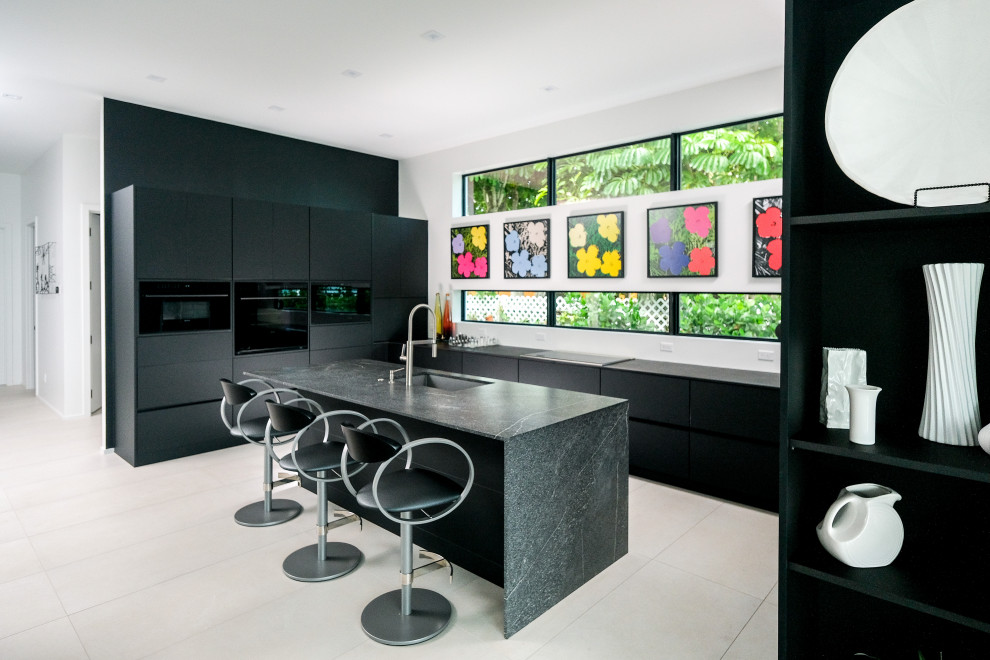 Photo of a medium sized contemporary u-shaped open plan kitchen in Miami with a single-bowl sink, flat-panel cabinets, black cabinets, quartz worktops, black appliances, porcelain flooring, an island, white floors and grey worktops.