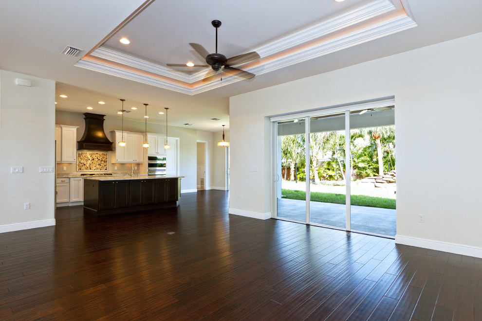 マイアミにある広いトロピカルスタイルのおしゃれなキッチン (アンダーカウンターシンク、落し込みパネル扉のキャビネット、白いキャビネット、珪岩カウンター、シルバーの調理設備、磁器タイルの床、茶色い床、グレーのキッチンカウンター) の写真