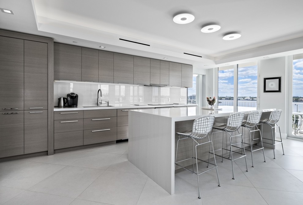 Trendy galley gray floor kitchen photo in Miami with an undermount sink, flat-panel cabinets, gray cabinets, white backsplash, paneled appliances, an island and white countertops