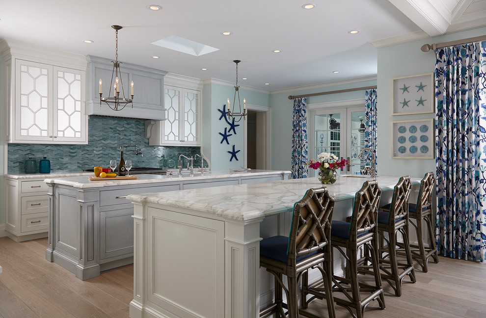 Bild på ett vintage linjärt kök, med luckor med infälld panel, vita skåp, marmorbänkskiva, blått stänkskydd, stänkskydd i mosaik, ljust trägolv och flera köksöar