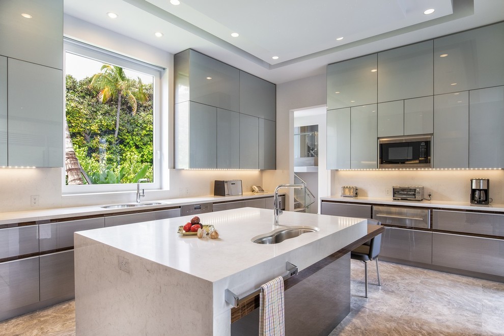 Moderne Küche in L-Form mit Unterbauwaschbecken, flächenbündigen Schrankfronten, grauen Schränken, Küchenrückwand in Weiß, Küchengeräten aus Edelstahl und Kücheninsel in Miami