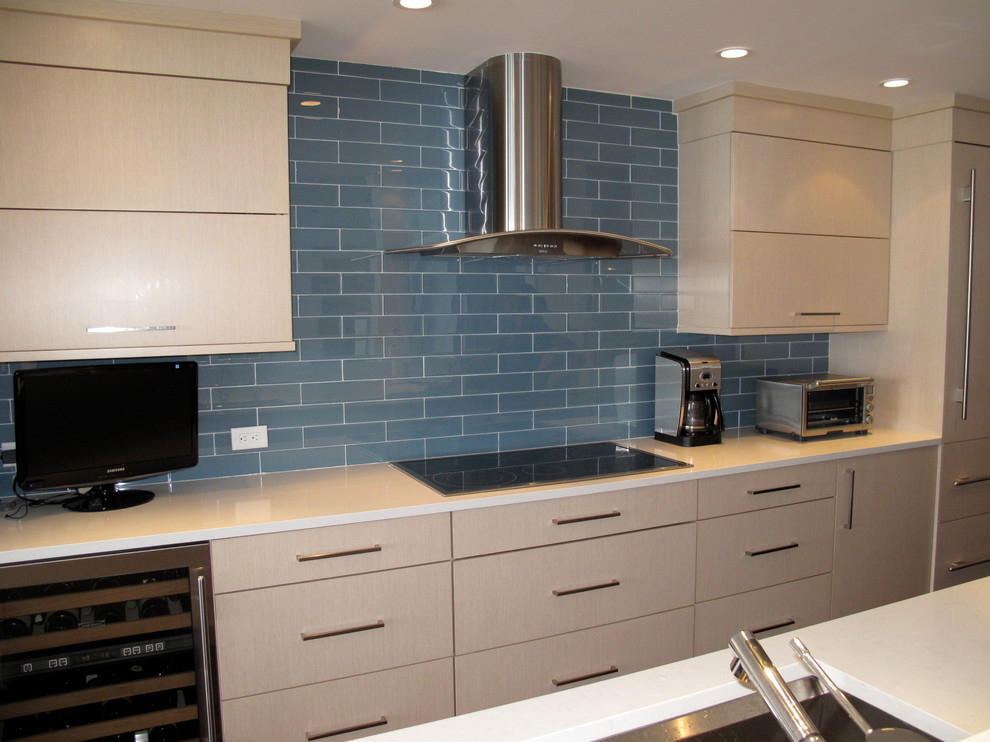 Modelo de cocina contemporánea de tamaño medio con fregadero de un seno, puertas de armario de madera clara, salpicadero azul, electrodomésticos de acero inoxidable y una isla