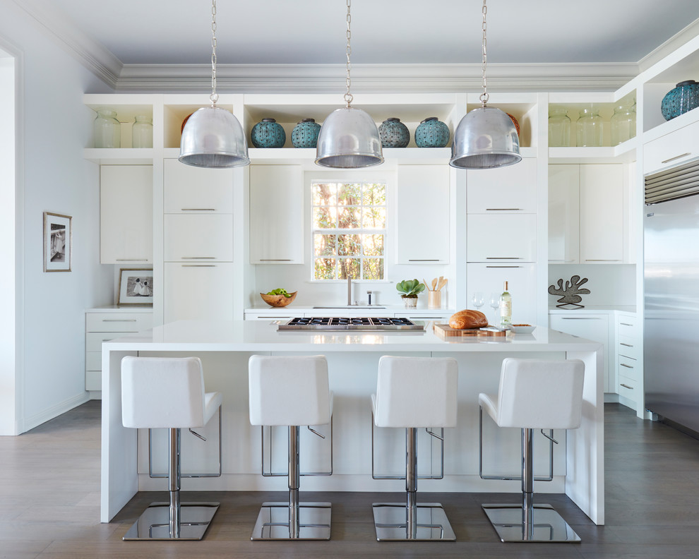 Bild på ett funkis l-kök, med en undermonterad diskho, släta luckor, vita skåp, vitt stänkskydd, rostfria vitvaror, mörkt trägolv, en köksö, brunt golv och bänkskiva i kvarts