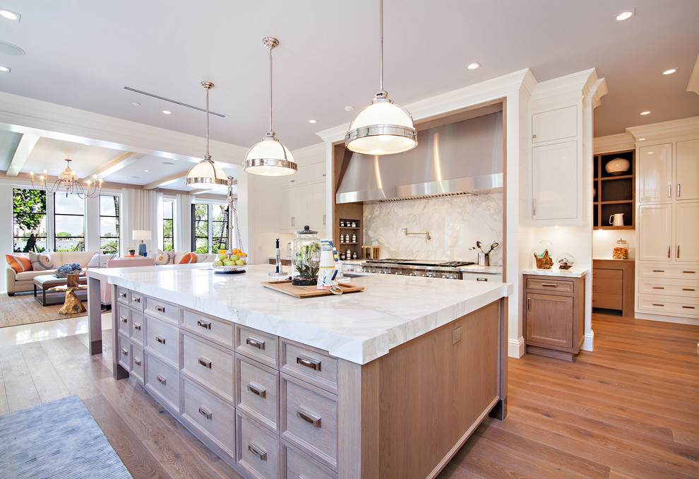 Inspiration for an expansive traditional kitchen in Miami with a submerged sink, shaker cabinets, white cabinets, marble worktops, white splashback, stone slab splashback, white appliances, medium hardwood flooring and an island.