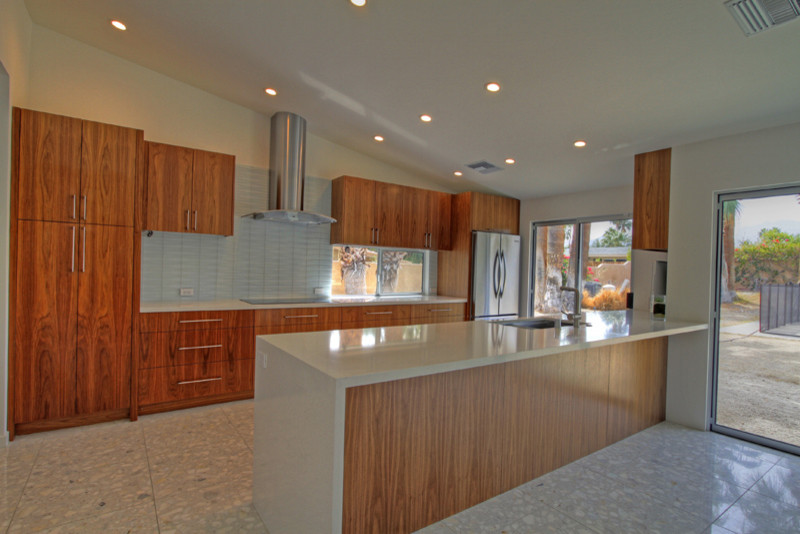 他の地域にある高級な中くらいなモダンスタイルのおしゃれなキッチン (フラットパネル扉のキャビネット、シルバーの調理設備、テラゾーの床) の写真