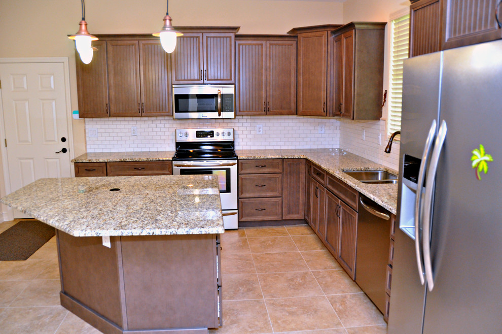 Example of a mid-sized transitional l-shaped ceramic tile and beige floor open concept kitchen design in Tampa with an undermount sink, louvered cabinets, dark wood cabinets, granite countertops, white backsplash, subway tile backsplash, stainless steel appliances and an island
