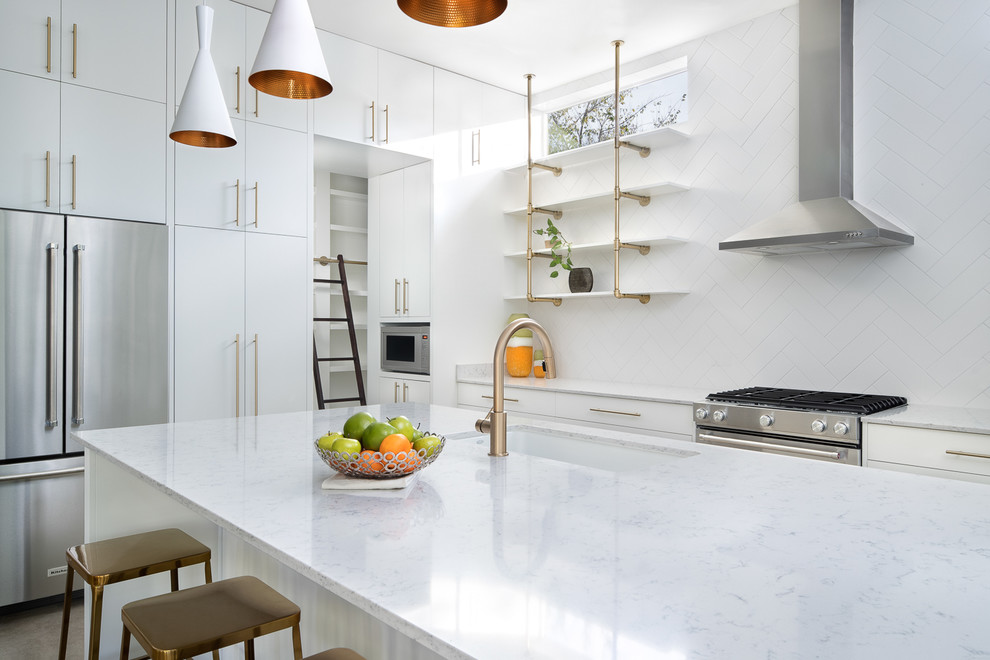 Inspiration for a large mid-century modern l-shaped concrete floor and gray floor eat-in kitchen remodel in Austin with a drop-in sink, flat-panel cabinets, white cabinets, marble countertops, white backsplash, ceramic backsplash, stainless steel appliances, an island and white countertops