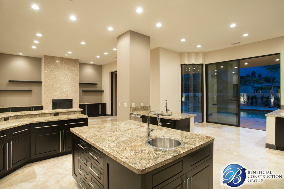 Large contemporary kitchen in Los Angeles with a built-in sink, flat-panel cabinets, black cabinets, granite worktops, stone slab splashback, stainless steel appliances, travertine flooring and an island.