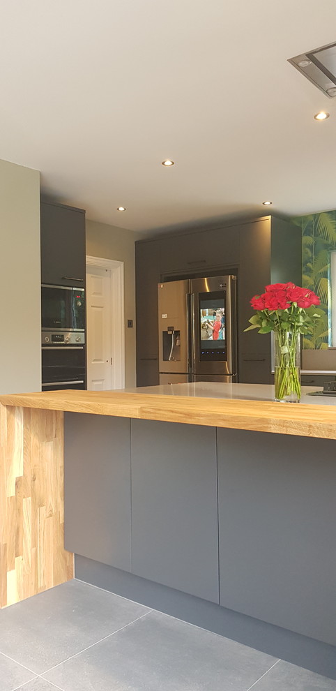 Inspiration for a medium sized contemporary open plan kitchen in Other with a built-in sink, flat-panel cabinets, grey cabinets, quartz worktops, stainless steel appliances, porcelain flooring, an island, grey floors and grey worktops.