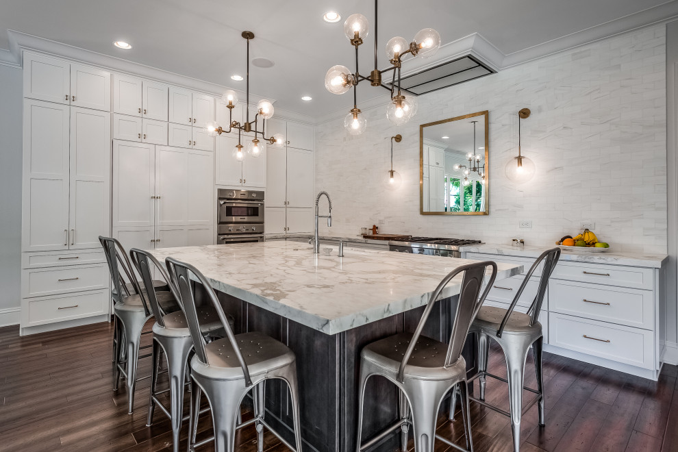 Inspiration for a transitional l-shaped medium tone wood floor open concept kitchen remodel in Tampa with a single-bowl sink, shaker cabinets, white cabinets, marble countertops, white backsplash, marble backsplash, paneled appliances, an island and white countertops