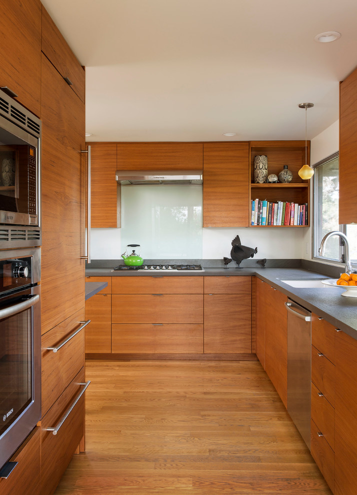 Diseño de cocinas en L contemporánea con fregadero bajoencimera, armarios con paneles lisos, puertas de armario de madera oscura, electrodomésticos de acero inoxidable y suelo de madera en tonos medios