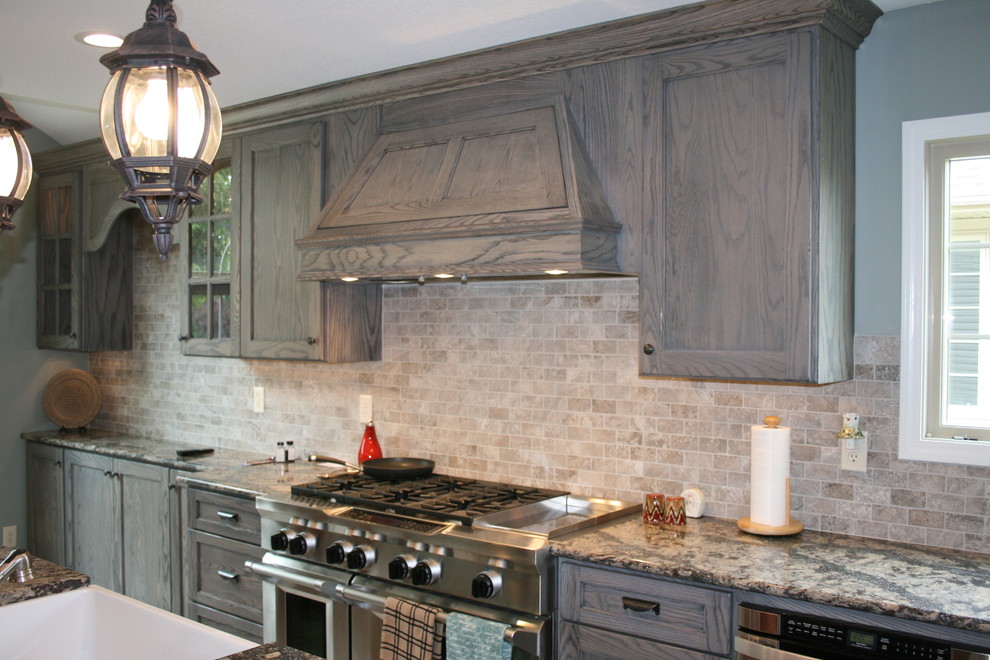 Eat-in kitchen - mid-sized traditional l-shaped dark wood floor eat-in kitchen idea in Other with a farmhouse sink, shaker cabinets, distressed cabinets, granite countertops, gray backsplash, stone tile backsplash, stainless steel appliances and an island