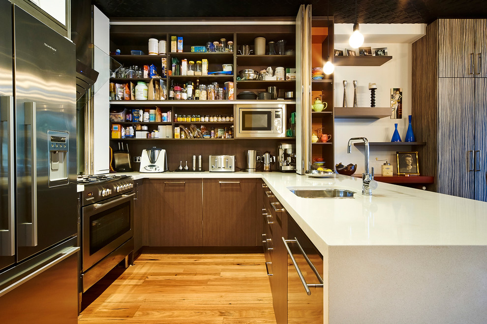Moderne Wohnküche in U-Form mit Unterbauwaschbecken, flächenbündigen Schrankfronten, dunklen Holzschränken, Küchengeräten aus Edelstahl und braunem Holzboden in Perth